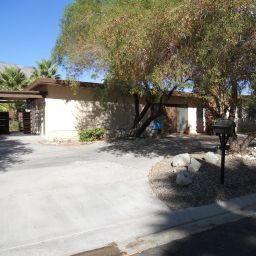 Single-story house with palm trees nearby.